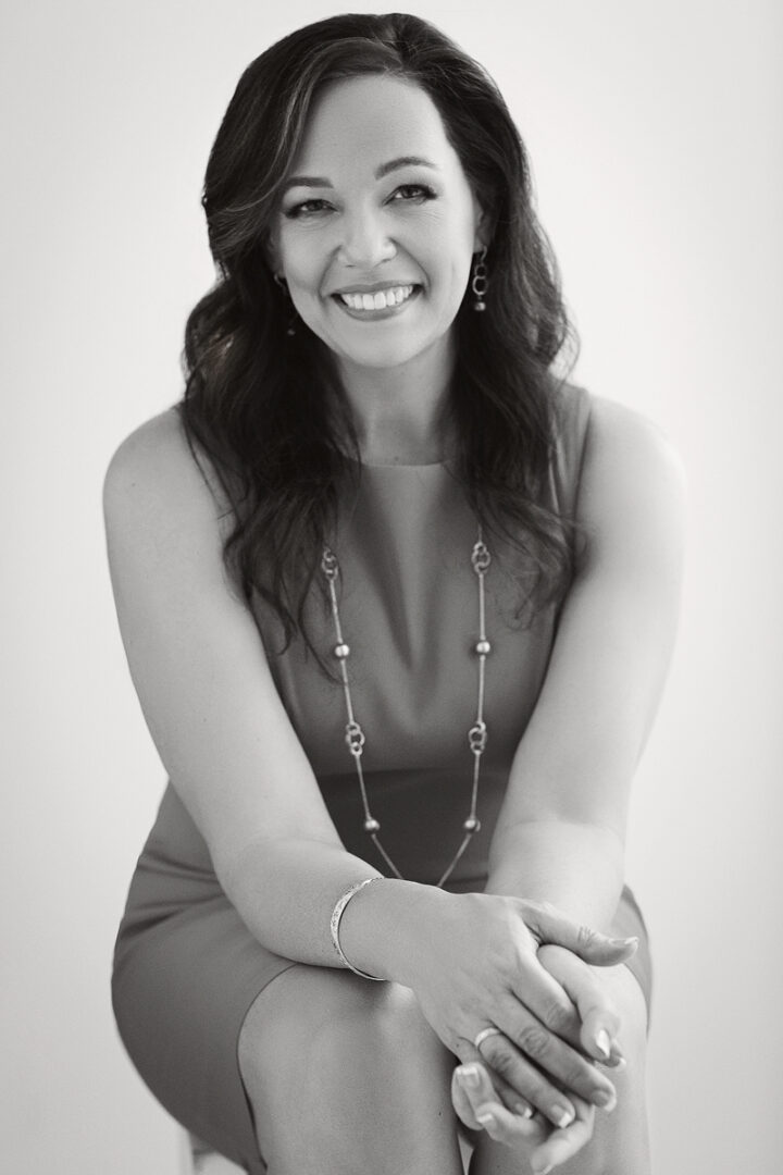 A woman with long hair and a necklace is smiling.