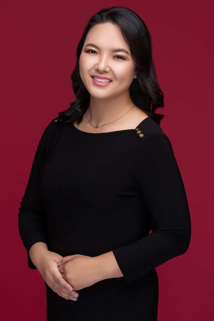 A woman in black shirt standing next to red wall.