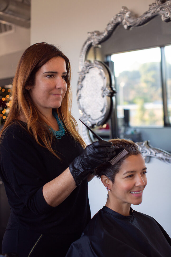 A woman is cutting the hair of another person.