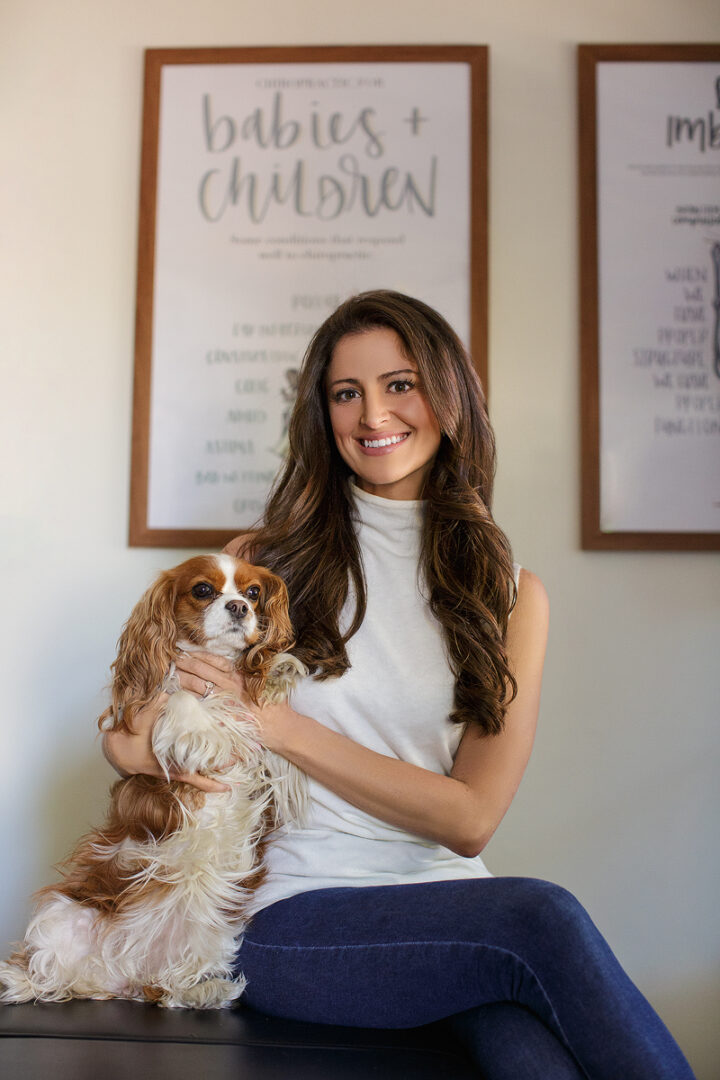 A woman holding her dog in front of some posters