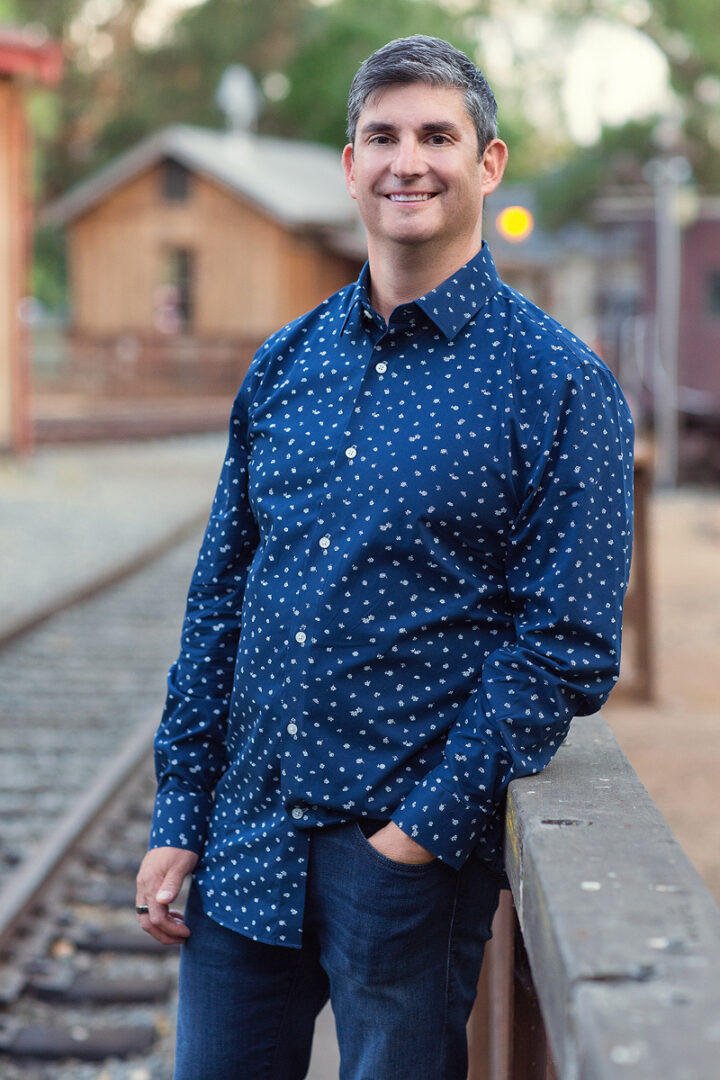 A man standing on the side of train tracks.