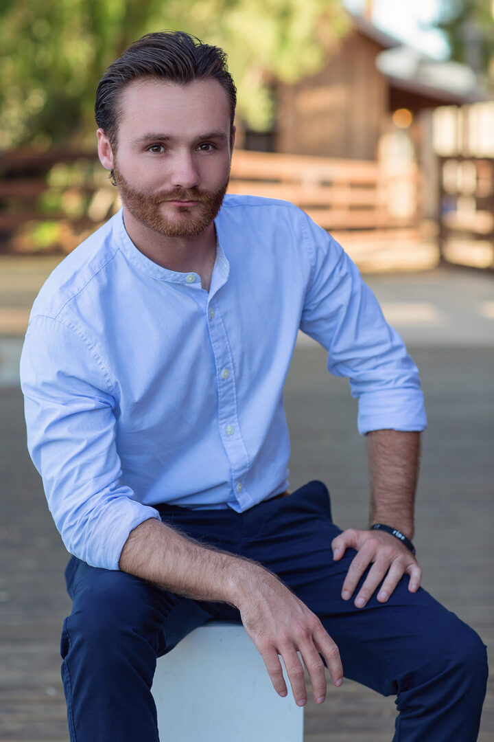 A man sitting on the ground wearing a white shirt.