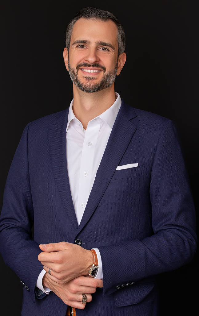 A man in a suit and tie smiling for the camera.