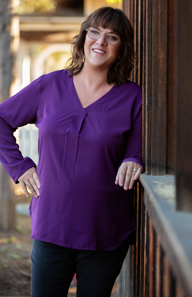 A woman leaning against the wall in front of a building.